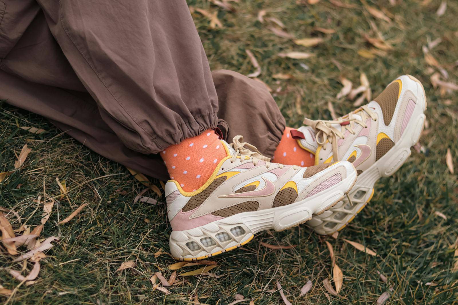 Stylish sneakers paired with orange socks in an autumn park setting.