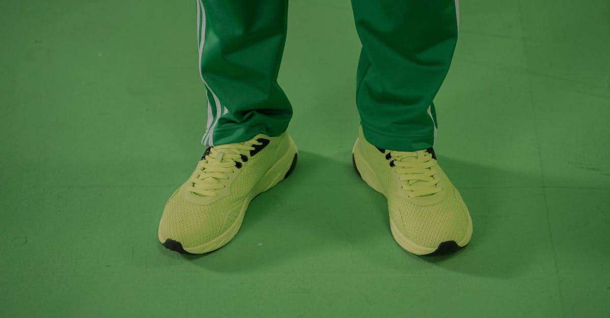 Close-up of neon yellow sneakers paired with green pants on a green surface.