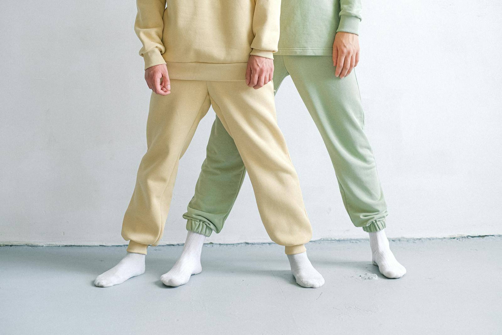 Studio shot showcasing minimalist fashion with two people in tracksuits and socks.